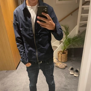 Mörkblå jacka från GANT - En riktigt snygg och trendig Overshirt från Gant, perfekt nu till våren/hösten. Det är en storlek 46 / M men passar även S. Nypris runt 1800.