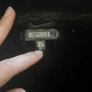 Svart jacka från Missguided - Säljer en snygg svart jacka från Missguided i storlek XS. Jackan har en cool bikerstil med dragkedjor och bältesdetaljer. Den är fodrad med mjukt material för extra värme. Perfekt för höst och vinter!