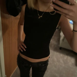 Svart ärmlös topp - Snygg svart ärmlös topp i tight passform. Perfekt för en utekväll eller sommarens varma dagar. Enkel och stilren design som passar till allt. Oanvänd.