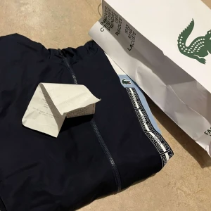 Lacoste kofta - Hej jag säljer en ÄKTA Lacoste kofta som aldrig använt. Koftan är i nyskick och har fortfarande alla sina taggar, koftan köptes men används inte. Med koftan kommer Lacoste påsen och kvittot. För mer frågor kom DM