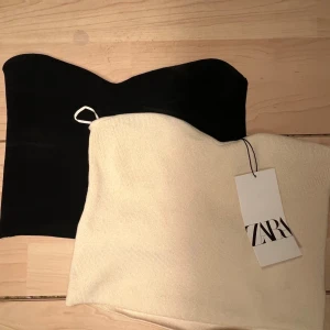 Svart och beige tubtopp från Zara - Säljer två snygga tubtoppar från Zara i storlek M. En är svart och den andra är beige. Perfekta för sommaren eller en utekväll. De är i nytt skick och har en enkel och stilren design. Passar bra till både jeans och kjol!
