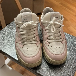Sneakers från Axel Arigato - Säljer ett par snygga sneakers från Axel Arigato i vitt och rosa. De har en klassisk design med snörning och är i bra skick. Perfekta för både vardag och festliga tillfällen. Tillverkade i Portugal.