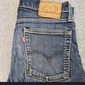 Levi's 510 jeans - Säljer ett par snygga Levi's 510 jeans i blå denim. De har en tight passform och är i bra skick. Perfekta för både vardag och fest! Snygga jeans från Levi's med stretch. Detta par är vintage dom har det stora E i ordet levis på den röda lappen och 1 rads innersöm på inre ben och är då vintage. De är i väldigt fint skick och Levis har superbra kvalitet på deras jeans. Blixtlås med 1 knapp.  bilder  för mått på Midja och beninnerlängd skickar jag ifall ni vill ha. Förmodligen 60 tal.