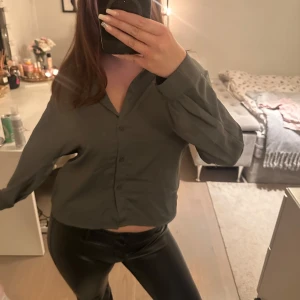 Grön skjorta med knappar - Säljer en grön satinliknande skjorta med knappar framtill. Skjortan har långa ärmar och en klassisk krage. Perfekt för en avslappnad men ändå uppklädd look.