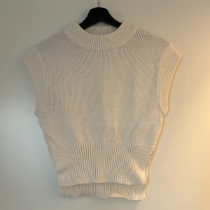 Stickad väst - Väldigt fin väst, sparsamt använd. Lite croppad modell med utskärningar på sidorna. Från Gina tricot.