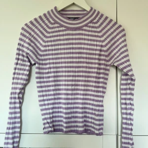Ribbad polotröja - GinaTricot  - Säljer en ribbad vit/lila randig polotröja o storlek M från GinaTricot. Sällan använd, mycket bra skick! 
