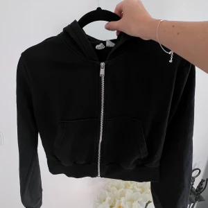 Croppad svart hoodie - En croppad svart hoodie med dragkedja. Lite liten i storleken då den passar mig som normalt har storlek S. Säljer den pga att den inte används längre 🌸  Längd: 41 cm Axel: 43 cm