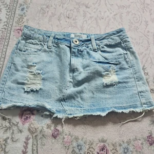 Minikjol - Söt minikjol med fina detaljer. Dock har den tunnare material än vanligt. Har även två andra kjolar på min sida Midjemått: 35 Längd: 29