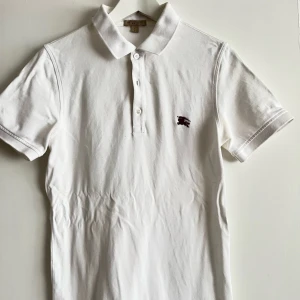 Pikétröja burberry - Burberry Emblem Broderad Pikétröja i Ecru Cotton. Behövs endast strykas. Märke: Burberry Skick: Mycket bra  Färg: Vit Storlek: S  Inga skam priser tack!!