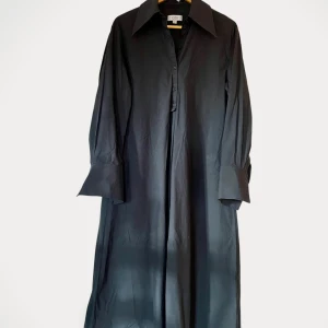 Cos klänning  - Klänning från Cos.  Storlek: 38 Material: Bomull Klänningen är helsvart (det är skuggor på bilden), men tvättpåverkad så som svarta plagg blir.