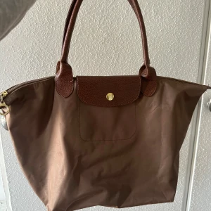 väska - säljer denna Longchamp liknande väska, köpt i spanien. Brun. Använd några gånger, har lite defekter (se bild tre), men syns inte jätte mkt, kanske går att tvätta bort? 🤎cirka 30-40 cm bred