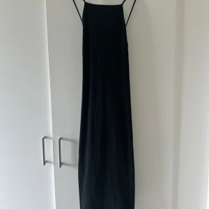 Klänning  - Svart lång klänning med kors i ryggen ifrån Gina Tricot, ny med utan prislapp. Strl M. 