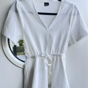 Vit blus - En vit blus från Gina Tricot med stretchigt material samt resår och en fin knytning i midjan. Normal i storleken 🥰  (ALDRIG ANVÄND)
