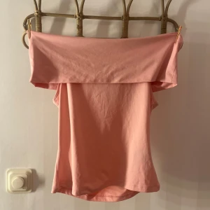Rosa offshoulder topp - Säljer en söt rosa offshoulder topp. Perfekt för varma dagar med sin ärmlösa design. Toppen har en enkel och stilren look som passar till många olika outfits.