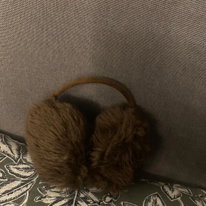 Bruna pälsöronmuffar - Snygga och varma bruna öronmuffar i pälsmaterial. Perfekta för att hålla öronen varma under kalla dagar. De har en enkel design med ett matchande brunt band.