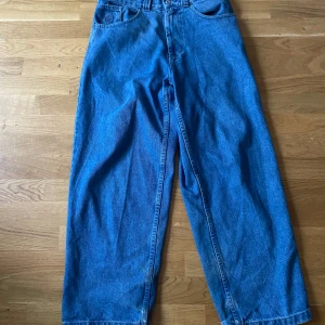 Loose Big Boy jeans  med råa kanter - Säljer ett par blå jeans med en loose passform och råa kanter vid bensluten. Perfekta för en avslappnad stil. Klassisk femficksdesign och knappgylf.