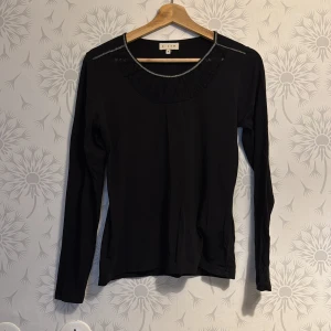 Svart långärmad topp med spetsdetaljer - Snygg svart långärmad topp från Esprit med spetsdetaljer vid halsringningen. Perfekt för en stilren look. Passar bra till både jeans och kjol.