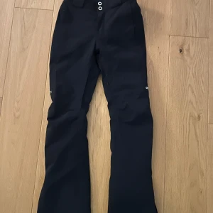 Svarta skidbyxor från dope snow - Snygga svarta skidbyxor från Dope Snow med en bootcut-stil. Byxorna har en högmidjad design och är tillverkade i ett slitstarkt material som håller dig varm och torr under hela skidsemestern. Säljer ett par i xxs och ett par i xs (båda annonserna finns uppe på min sida)⭐️Nypris 1800kr
