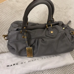 Marc Jacobs väska - Så snygg och eftertraktad väska från Marc Jacobs i nyskick! Så fin grå färg med gulddetaljer❣️❣️
