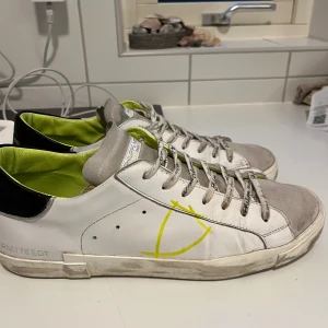 Philippe Model - Snygga vita sneakers från Philippe Model med grå detaljer och en gul insida. Skorna har en unik design med handskriven text på snörningen. Väldigt feta nu till våren.