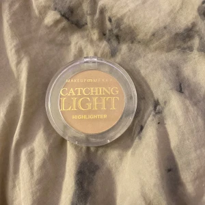 Catching Light Highlighter från Makeup Mekka - Snygg highlighter från Makeup Mekka i nyansen 'Catching Light'. Perfekt för att ge ansiktet en strålande glöd. Kommer i en praktisk rund förpackning med genomskinligt lock. Har använd den några gånger bara 