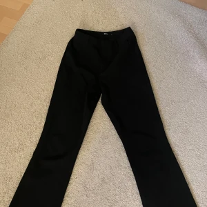Svarta byxor från Bik Bok - Snygga svarta byxor från Bik Bok i en klassisk design. Perfekta för en stilren look. Byxorna är utsvängda och låg midjade 