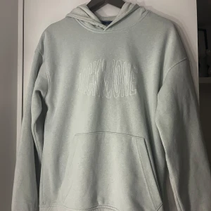 Ljusblå hoodie från Jack & Jones - Säljer en stilren ljusgrå hoodie från Jack & Jones. Tröjan har en klassisk design med en stor ficka framtill och en luva. Perfekt för en avslappnad look. Nypris 800kr, säljer nu för 600. Pris går att diskutera 