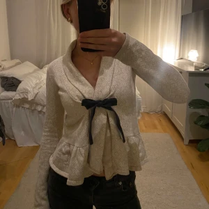 Beige kofta från Odd Molly - Säljer en elegant beige kofta från Odd Molly med ett diskret mönster och en söt rosett framtill. Koftan har långa ärmar och en volangdetalj vid nederkanten. Perfekt för en stilren look. Super söt kofta från odd Molly. Jätte jättesöt men jag har inte använt den på länge tyvärr. Den är i strl 0 och motsvarar ungefär Xs! Hör av dig om du är intresserad❤️