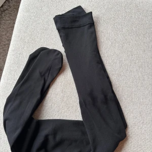 Svarta thermo strumpbyxor  - Säljer ett par svarta strumpbyxor. De är långa och har en mjuk och stretchig kvalitet. Perfekta för att hålla benen varma och stiliga under kyligare dagar. Knappt använd men finns lite slitage vid fötterna 