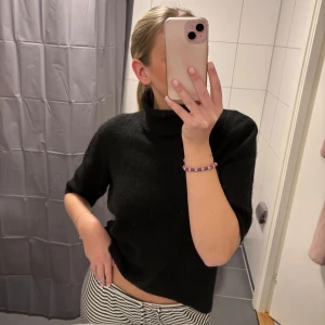 Svart polotröja - Säljer en stilren svart polotröja med trekvartsärm. Perfekt för en elegant och avslappnad look. Tröjan har en mjuk och bekväm passform.