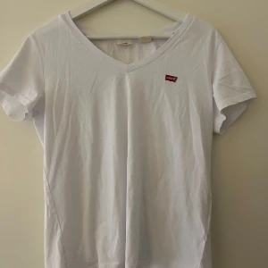Vit t-shirt från Levi's - Jättesöt vit t-shirt från Levi's med v-ringning och korta ärmar. Den har en liten röd Levi's-logga på bröstet. Skriv för fler bilder eller för bild på!❤️
