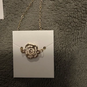 Guldigt rosformat smyckeset - Elegant smyckeset i guld med rosformade detaljer. Setet inkluderar ett halsband och matchande örhängen, perfekt för att ge en romantisk touch till din stil.