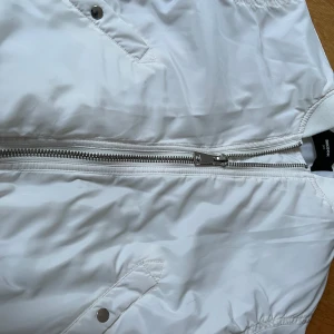 Vit bomberjacka från Bik Bok - Snygg vit bomberjacka från Bik Bok i storlek XS. Jackan har en dragkedja framtill och ribbade muddar vid ärmslut och nederkant. Perfekt för en stilren look.