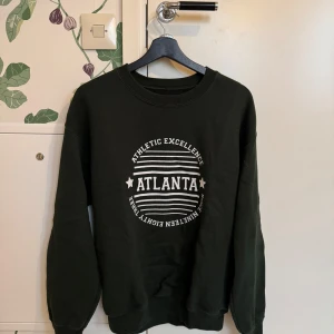 Svart sweatshirt från Daisy Street - Säljer en svart sweatshirt från Daisy Street med tryck 'Atlanta' på framsidan. Tröjan har långa ärmar och en rund halsringning. Perfekt för en avslappnad stil.