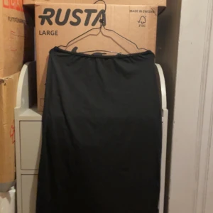 Svart långkjol - Elegant svart långkjol med enkel design. Perfekt för en stilren look. Kjolen har en elastisk midja för bekväm passform. Och det går att anpassa midjan på den så går att ha nåde högmodjad och lågmidjad