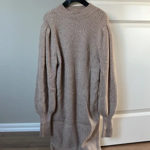Beige ribbad stickad klänning - Säljer en stilren beige stickad klänning med ribbad struktur. Klänningen har långa ballong ärmar. Använd 2 tillfällen. Perfekt till jul och nyår!🎄🌟