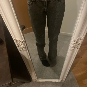 Lågmidjade Grå jeans med slitning - Använd fåtal gånger. Säljer ett par grå jeans med en cool slitning på ena benet. De har en straight passform och är perfekta för en avslappnad stil. Jeansen har klassisk femficksdesign och knappgylf.