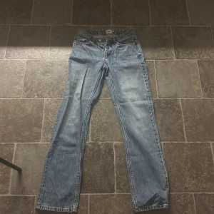 Blå jeans från Lager 157 - Säljer ett par klassiska blå jeans från Lager 157 med rak passform. De har en traditionell femficksdesign och knappgylf. Perfekta för en avslappnad stil. Dom är lite skrynkliga eftersom dom legat intryckta i en garderob under en längre tid men det går bara att stryka så är dom som nya!