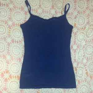 Mörkblå linnetopp från HEMA - Snygg mörkblå linnetopp från HEMA med spetsdetaljer vid halsringningen. Tillverkad i en mjuk bomullsblandning med elastan för extra komfort. Perfekt för en avslappnad stil.