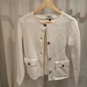 Vit kavaj från Hampton Republic - Snygg vit kavaj från Hampton Republic med rund hals och knappar framtill. Den har två praktiska fickor med knappar och är perfekt för en stilren look.