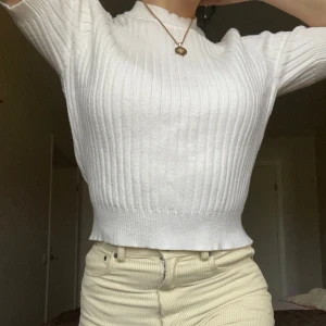 Vit ribbad tröja - Snygg vit ribbad tröja med korta ärmar och croppad passform. Perfekt för en stilren look.