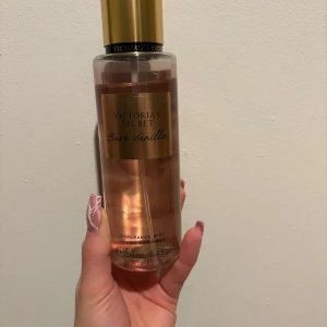 Bare Vanilla Fragrance Mist från Victoria's Secret - Säljer en Bare Vanilla Fragrance Mist från Victoria's Secret. Den har en söt och krämig doft av vispad vanilj och mjuk kashmir. Flaskan är genomskinlig med en gyllene kork och rymmer 250 mlfrån början.