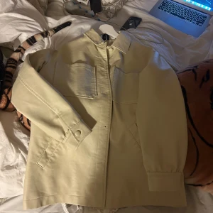 Creme vit jacka - Snygg creme vit  jacka från Collusion, köpt på ASOS.  Den har långa ärmar och knappar framtill. Perfekt för en stilren look. Jackan har praktiska fickor och en klassisk krage.