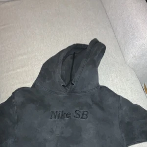 Svart hoodie från Nike SB - Säljer en svart hoodie från Nike SB med broderad logga på bröstet. Den har en klassisk design med huva och långa ärmar. Perfekt för en avslappnad stil.