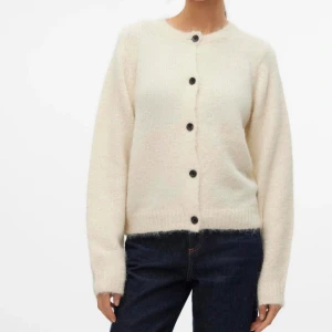 Vit stickad kofta från Vero Moda - Mysig krämvit stickad kofta från Vero Moda med svarta knappar framtill. Använd ett fåtal gånger, jätte gosig och fin kofta.