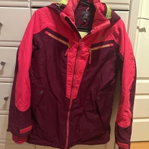 Rosa och lila jacka med huva - Ett skiställ med jacka och byxor med hängslen, helt och rent förutom lite defekter på rumpdelen (smuts som inte riktigt gått att ta bort, syns knappt) säljer då de blivit för litet.