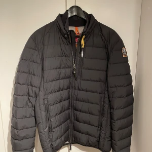 UGO - SHORT DOWN JACKET från Parajumpers - Snygg svart pufferjacka från Parajumpers. Jackan är lagom tjock för höst och vår väder och har endast använt den 1 år, både höst och vår. Ordinarie pris för jackan är 5499kr men köpte den på rea för 4299kr. Jackan har en liten skada på insidan där det har börjat komma ut lite fjädrar, så har lappat ihop det med en  lagningslapp som har hållit perfekt. (Det syns på andra bilden) Resten av jackan är hel och har inga större defekter. Säljer jackan då den har blivit för liten för mig.