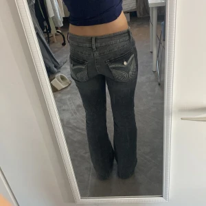Grå bootcut jeans med broderade fickor - Super Snygga slutsålda grå bootcut jeans med unika broderade detaljer på bakfickorna. De har en låg midja och en klassisk femficksdesign. Perfekta för en avslappnad stil med en twist. Storlek 164 men passar S också. Nypris 399