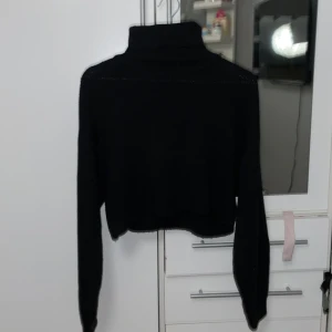 Svart croppad polotröja från H&M Divided - Snygg svart croppad polotröja från H&M Divided. Perfekt för en stilren look med långa ärmar och hög krage. Enkel att matcha med olika outfits.