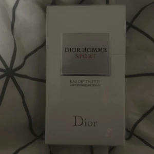 Dior Homme Sport Eau de Toilette - Säljer en elegant Dior Homme Sport Eau de Toilette. Denna parfym kommer i en stilren vit förpackning med klassisk design. Perfekt för den moderna mannen som vill ha en fräsch och sportig doft.